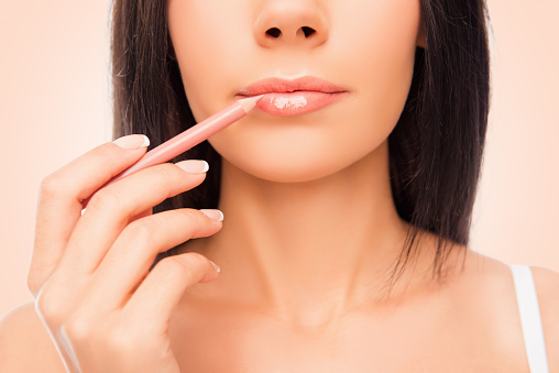 Primer plano de una mujer joven haciendo maquillage con forr de labios photo
