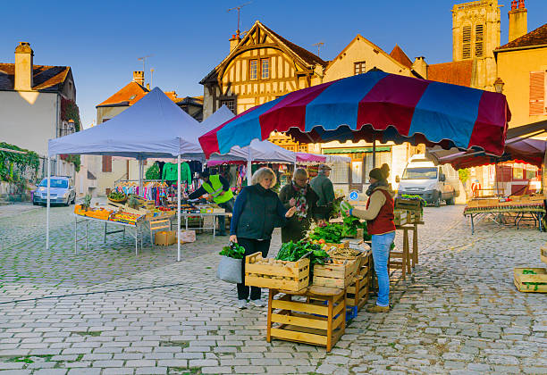Market scene in the medieval village Noyers-sur-Serein Noyers-Sur-Serein, France - October 12, 2016: Market scene with sellers and shoppers, in the medieval village Noyers-sur-Serein, Burgundy, France avallon stock pictures, royalty-free photos & images