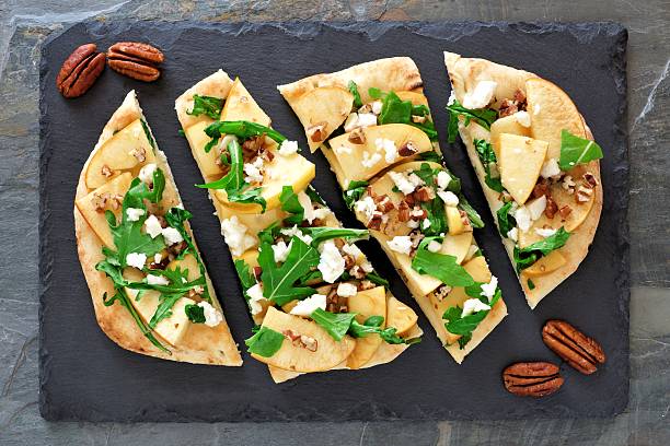 Flat bread with apples, arugula, above view on slate server Flat bread with apples, arugula, feta and pecans, above view on slate server flatbread stock pictures, royalty-free photos & images