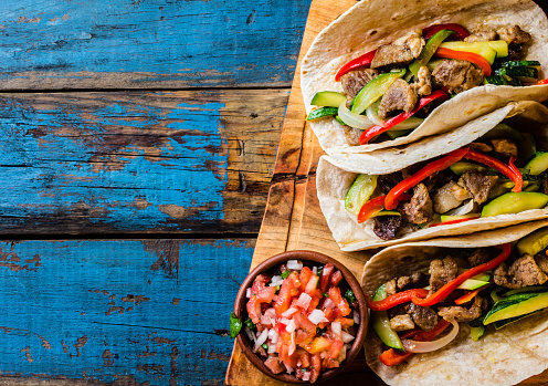 Mexican pork tacos with vegetables and salsa. Tacos al pastor on wooden blue rustic background. Top view. Copy space