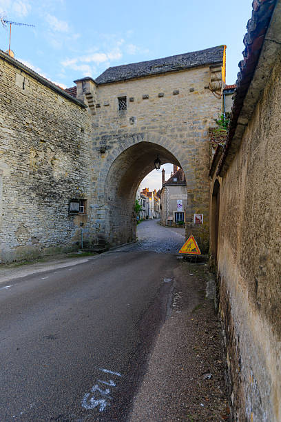 The north gate in the medieval village Noyers-sur-Serein Noyers-Sur-Serein, France - October 11, 2016: Sunset view of the north gate (La Porte de Tonnerre), in the medieval village Noyers-sur-Serein, Burgundy, France avallon stock pictures, royalty-free photos & images