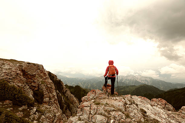 successful woman backpacker hiking on mountain peak cliff