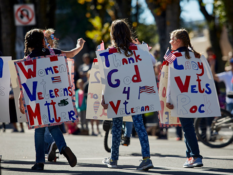 Prescott, Arizona, United States - November 11, 2016: Young girls wearing signs supporting veterans marching in Veterans day parade
