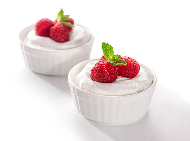 bowl of cream with raspberries close-up on white background