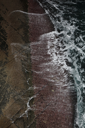 Cool photo with three parts. First part is just a concrete, second is alot of pink algaes and third waves coming in from the ocean. Photo is take in Italy in Cinque Terre.