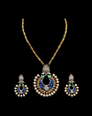Close up of a complete set of Gold and Diamond necklace with beautiful diamond earrings. Isolated on black background.