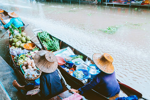 Damnoen Saduak floating market, Thailand - April 01, 2018: Tourists and sellers on boat floating through small canal in traffic jam at Damnoen Saduak floating market near Bangkok