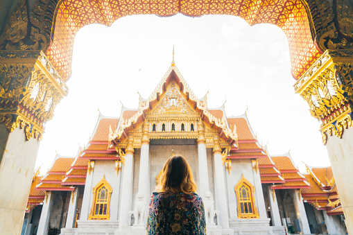 Young Caucasian Woman looking at Wat Pho temple at sunrise Bangkok, Thailand 