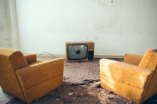 par de sofás en desuso frente a un televisor roto - slum living fotos fotografías e imágenes de stock