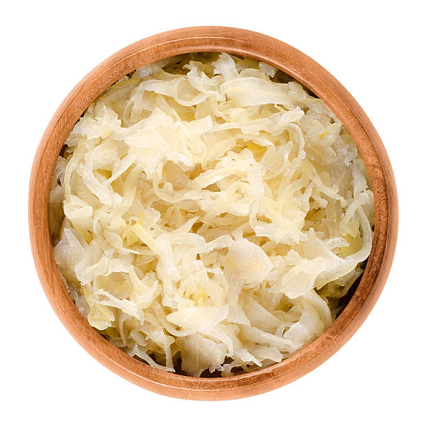 German sauerkraut in wooden bowl over white German sauerkraut in wooden bowl over white. Finely cut cabbage, fermented by lactic acid bacteria with long shelf life and distinctive sour flavor, used as a side dish. Isolated macro food photo. fermenting stock pictures, royalty-free photos & images