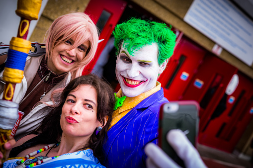 Sheffield, UK - June 11, 2016: Cosplayers dressed as 'Lighning' and 'Fang' from 'Final Fantasy Xiii' pose for a selfie with a host & entertainer 'Jimcredible' dressed as the 'Joker' from 'Batman' at the Yorkshire Cosplay Convention at Sheffield Arena