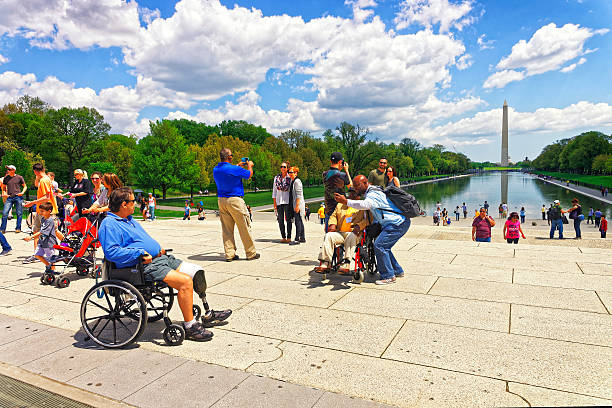 Washington DC, USA - May 2, 2015: War Veteran and his guardian of Honor Flight at Lincoln Memorial Reflecting Pool. Washington Monument on the background.