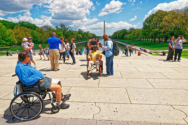 Washington DC, USA - May 2, 2015: War Veteran and his guardian of Honor Flight next to Lincoln Memorial Reflecting Pool. Washington Monument on the background.
