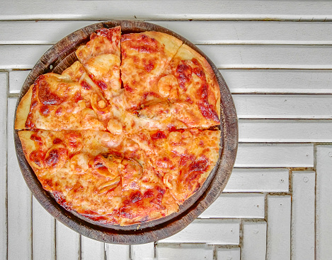 Closeup photo of fresh pizza seafood on wooden plate  and white wooden table.