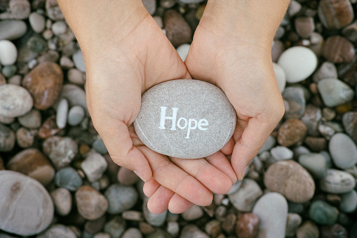 Hope. Woman holding stone with the word Hope in her palms. Close up.