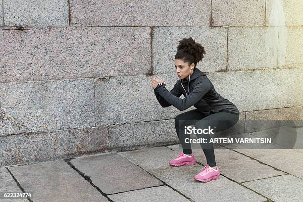 Sporty Woman Doing Warm Up Squat Stretching Near A Wall Stock Photo - Download Image Now