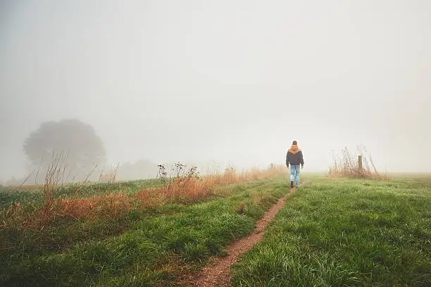 Lonely young man walking in mysterious fog. Autumn morning in beautiful nature in the Czech Republic