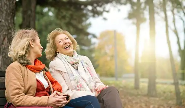 Two laughing senior friend relaxing at the park