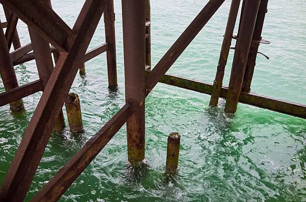 fragment construction. metal posts, rusty metal pier, sea water green