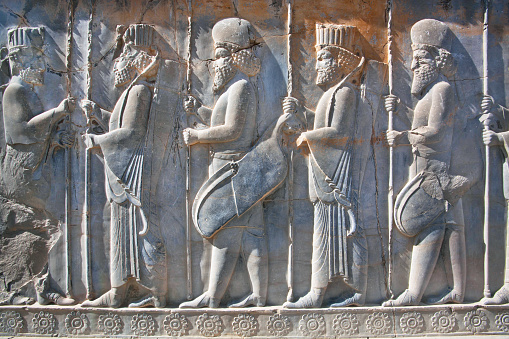 Soldiers of historical empire with weapon in hands. Stone bas-relief in ancient city Persepolis, Iran. Capital of the Achaemenid Empire, 550 - 330 BC. UNESCO declared Persepolis a World Heritage Site