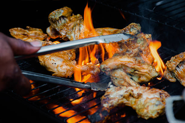 Chef cooking jerk barbecue BBQ chicken grilled hand turning food stock photo