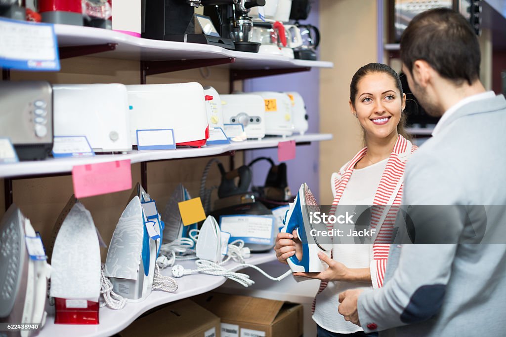 spouses choosing new clothes iron young spouses choosing new clothes iron in supermarket Iron - Appliance Stock Photo