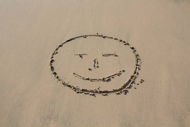 istock Smiley face drawn in the sand on the beach 622440158