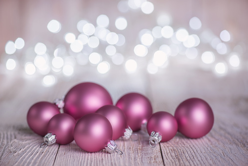 Pink Christmas Ornaments on old white Wood Background and defocused lights
