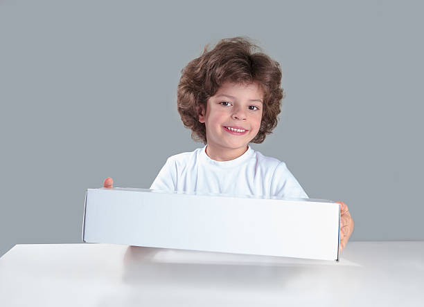 istock Cute curly little boy smiling presents white box. Gray background. 622445478