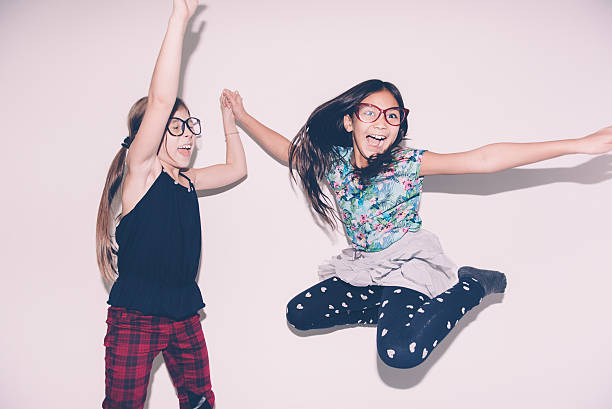 ragazze che saltano sul letto - two girls only cheerful front view horizontal foto e immagini stock