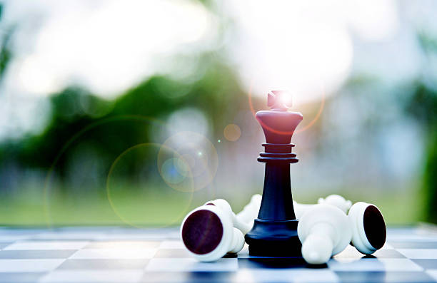 rei do xadrez negro entre peões brancos deitados - chess defending chess piece chess board - fotografias e filmes do acervo