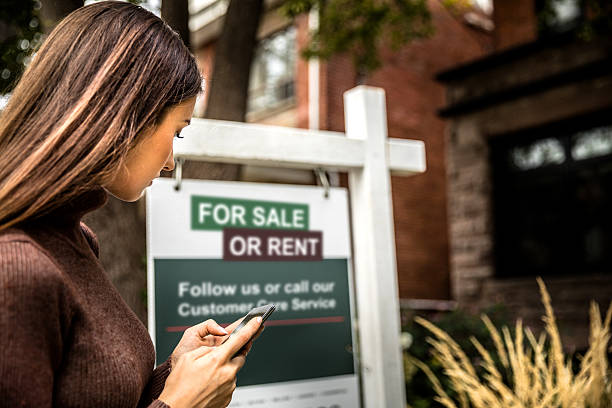 House for sale in the city downtown Woman photographing a real estate sign for a nice house for sale in downtown. houses for sale stock pictures, royalty-free photos & images