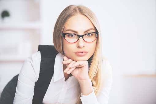 Portrait of focused young businesswoman in formal outfit and eyeglasses
