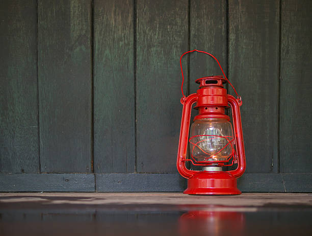a red old lantern on the dark wet wooden floor with reflection on the floor