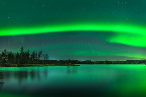 Aurora Borealis dancing in Northern Canada. The Northern Lights above a lake in Alberta Canada.