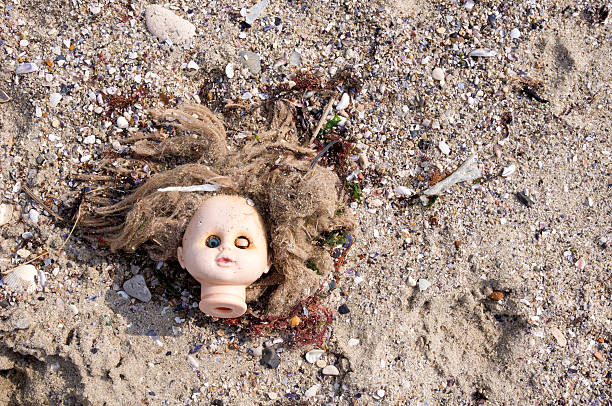 Head of children's doll thrown by the sea  on the beach trash