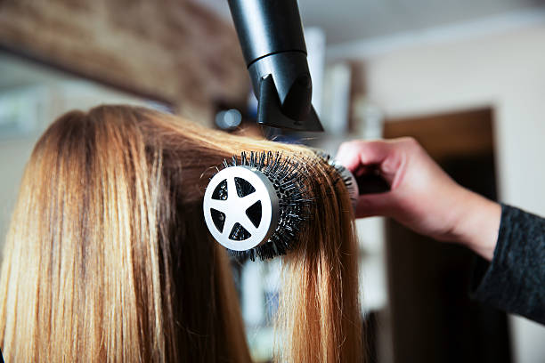 Fazendo penteado usando secador de cabelo. - foto de acervo