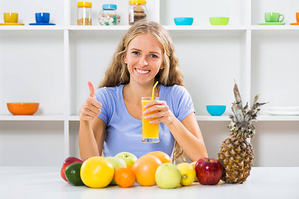 Beautiful girl drinking orange juice and showing thumb up
