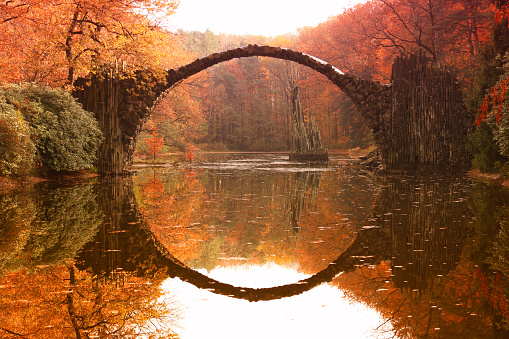 Rakotz bridge (Rakotzbrucke, Devil's Bridge) in Kromlau, Saxony, Germany. Colorful autumn, reflection of the bridge in the water create a full circle