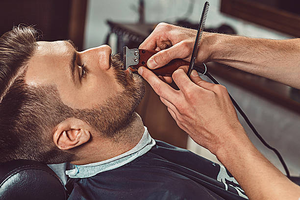 Hipster client visiting barber shop Hipster client visiting barber shop. The hands of young barber making the cut of beard barber stock pictures, royalty-free photos & images