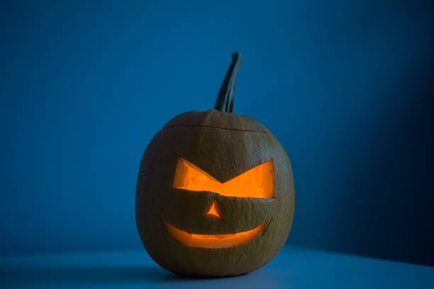 istock Scary Halloween pumpkin with eyes glowing inside at dark blue 622528324
