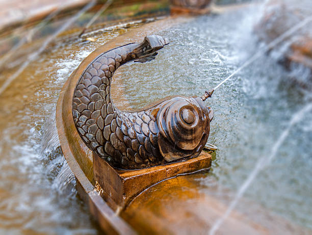 istock Bronze shape of fish with water shooting from mouth 622534094