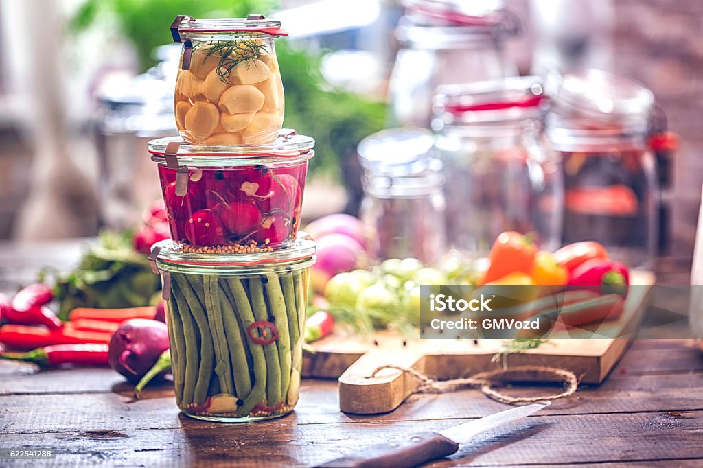 Preserving Organic Vegetables in Jars Preserving organic vegetables in jars like grean beans, garlic, carrots, cucumbers, tomatoes, chilis, paprika and radishes. Fermenting Stock Photo