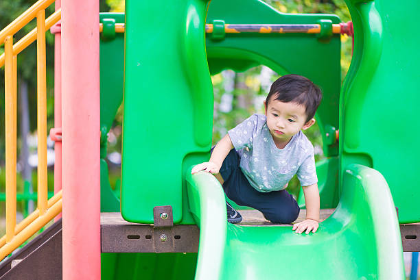 istock Little Asian kid playing slide at the playground 622542050