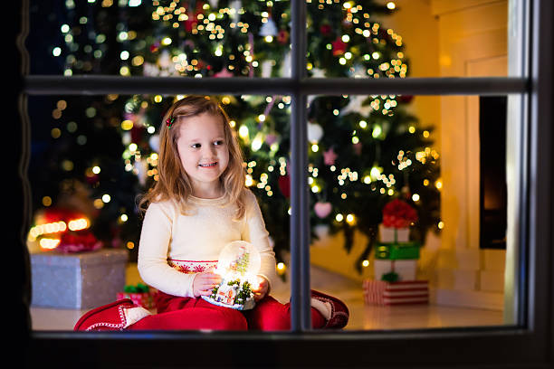 istock Little girl holding snow globe under Christmas tree with gift 622544550