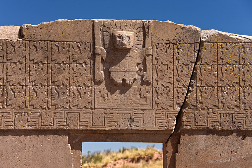 La Paz, Bolivia - April 26, 2008: A 2000 year old archway at Tiwanaku Pre-Inca site near La Paz in Bolivia, South America. Tiwanaku (Tiahuanaco or Tiahuanacu) is a Pre-Columbian archaeological site. The 'Gate of the Sun' is a megalithic solid stone arch or gateway constructed by the ancient Tiwanaku people over 1500 years ago. Some elements of Tiwanaku iconography spread throughout Peru and parts of Bolivia. Although there have been various modern interpretations of the mysterious inscriptions found on the object, the carvings that decorate the gate are believed to possess astronomical or astrological significance and may have served as a calendar.