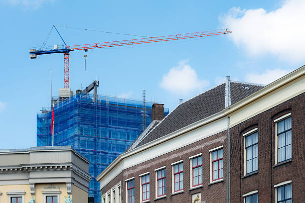 Modern  building site scaffolding  with blue covers and large crane behind classic dutch buildings in utrecht