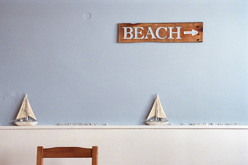 Two models of sailing boats decorate a wall. A direction sign points to the beach.