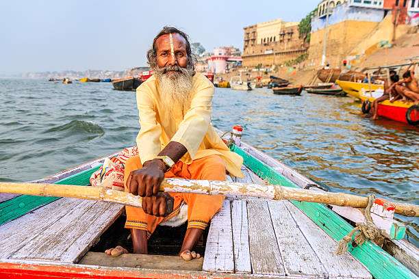 sadhu bateau d'aviron sur le fleuve gange sacrée de varanasi - india ganges river indian culture varanasi photos et images de collection