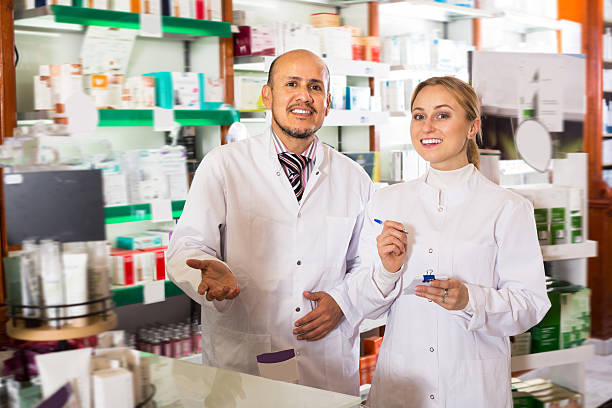 istock Two smiling pharmacists standing next to shelves 622789532